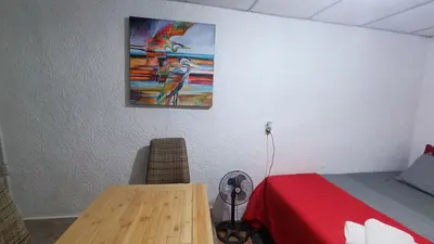 a bedroom with a bed and a table and a painting at Studio Suite 3, Buena Vista, Santa Tecla in Nueva San Salvador