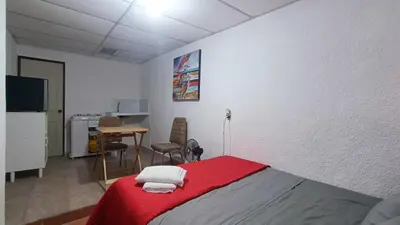 a bedroom with a bed with a red blanket at Studio Suite 3, Buena Vista, Santa Tecla in Nueva San Salvador