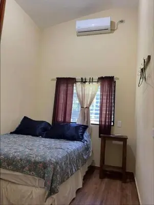 a bedroom with a bed with blue pillows and a window at DONDE ANTONIO BARRA DE SANTIAGO in Barra de Santiago