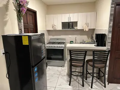 a kitchen with a refrigerator and a counter with chairs at Placentero y acogedor apartamento en Calle Monserrat in San Salvador