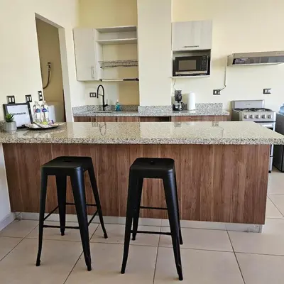 a kitchen with two black stools at a counter at Apartamento Centrico Colonia Escalón in San Salvador