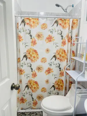 a shower curtain with orange flowers on it in a bathroom at Holiday home in San Miguel