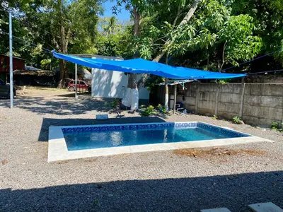 a swimming pool with a blue umbrella in a yard at Eco Villa, El Sunzal ISA Surfing in El Sunzal