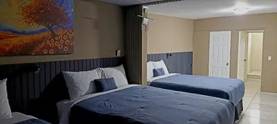 a bedroom with two beds and a painting on the wall at Kartagus B&B in San Salvador