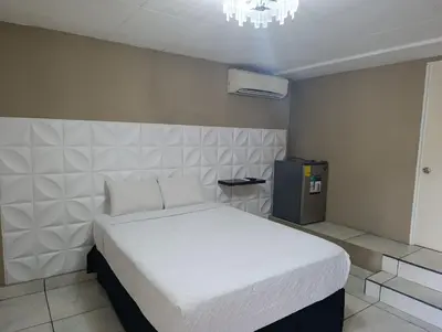 a bedroom with a white bed and a chandelier at Kartagus B&B in San Salvador