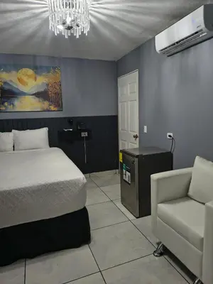 a bedroom with a bed and a chair and a chandelier at Kartagus B&B in San Salvador