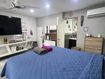 a bedroom with a blue bed and a flat screen tv at Smart and Modern Room Full Amenities in San Salvador in San Salvador