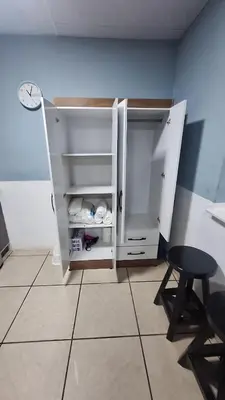 a white cabinet with a stool and a table in a room at Pearl of the sea in La Libertad
