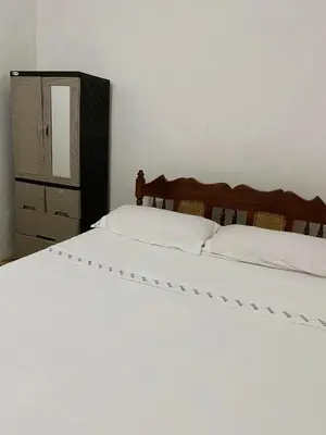 a white bed with a wooden headboard and a dresser at Aguiñada's House in El Rosario