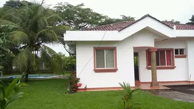 a white house with a palm tree in a yard at Casa de Playa en residencial las Veraneras San Fer in Los Cóbanos