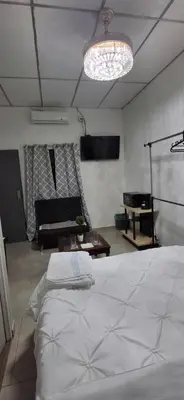 a bedroom with a white bed and a living room at Apartamento Moderno y Privado in Santa Ana