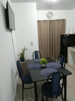 a dining room table with blue chairs and a television at Casa de Reyes in San Miguel