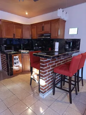 a kitchen with a brick counter and red chairs at Dinos House in Concepción de Ataco