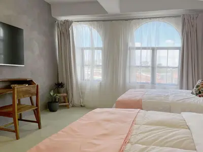 a bedroom with two beds and a desk and a window at Ipan Noya in Nueva San Salvador