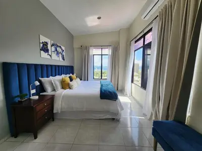 a bedroom with a large bed and a large window at Complete, Centrally-located apartment with panoramic view in San Salvador