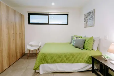 a bedroom with a green bed with a desk and a window at Cielo 404 in San Salvador
