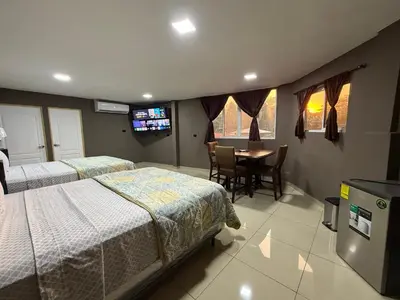 a bedroom with two beds and a table and a television at El Mangal 3 B&B in Suchitoto