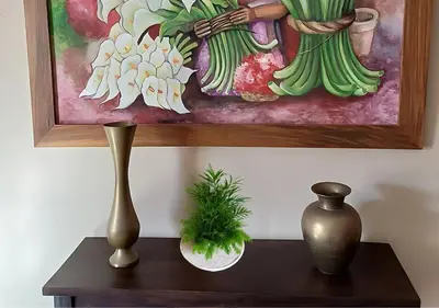 a table with a vase and a painting on a wall at \u30c4 Izalco Volcano Suites in Izalco
