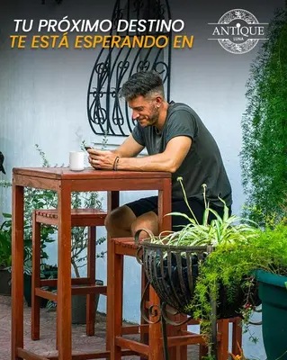a man sitting at a table with a phone at Hostal Antique Luna in Santa Ana