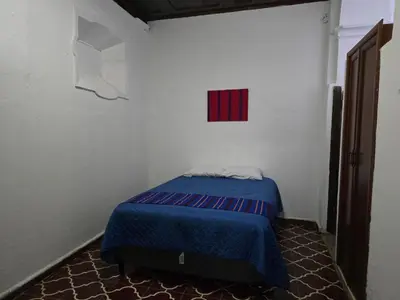 a bedroom with a blue bed in a white room at Hostal Antique Luna in Santa Ana