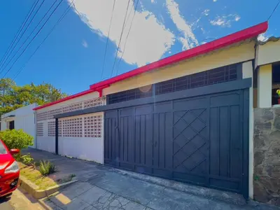a garage with a black garage door on a house at Casa de Helen in Antiguo Cuscatlán