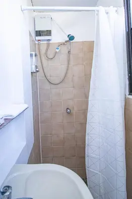 a bathroom with a shower with a toilet and a sink at Casa de Helen in Antiguo Cuscatlán