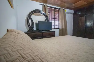 a bedroom with a bed and a mirror and a television at Casa de Helen in Antiguo Cuscatlán