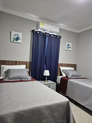 a bedroom with two beds and a window with blue curtains at Livo house in San Salvador in San Salvador