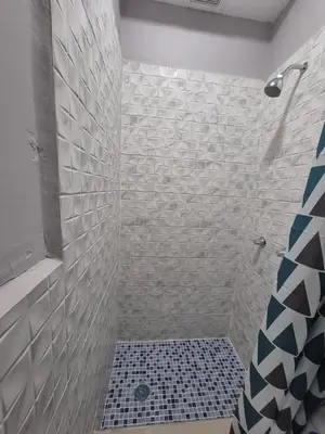 a bathroom with a shower with a black and white tiles at Livo house in San Salvador in San Salvador
