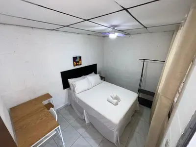 a small bedroom with a white bed and a table at Luxury Hostel Teresita in San Salvador