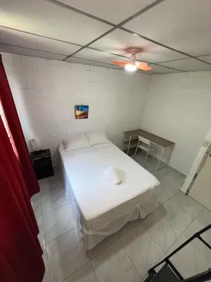a bedroom with a white bed and a ceiling fan at Luxury Hostel Teresita in San Salvador
