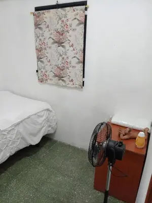 a room with a bed and a fan next to a desk at La Chola, Guest House in Santa Ana