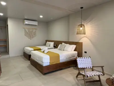 a bedroom with two beds and a chair at Litos Hotel in La Libertad