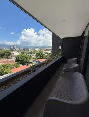 a balcony with chairs and a view of a city at Escalon apartment in San Salvador