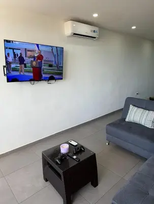 a living room with a couch and a tv on a wall at Escalon apartment in San Salvador