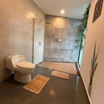 a bathroom with a shower with a toilet and mats at St Michaels Ocean View House in El Zonte