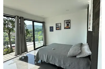 a bedroom with a bed and a large window at St Michaels Ocean View House in El Zonte
