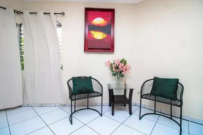 a room with two chairs and a table with flowers on it at Modern Stylish Apt in Secure Area in San Salvador in San Salvador