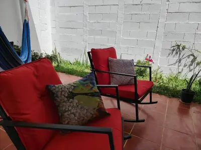 two chairs and a red couch on a patio at Susana's house, your home in Ahuachapán in Ahuachapán