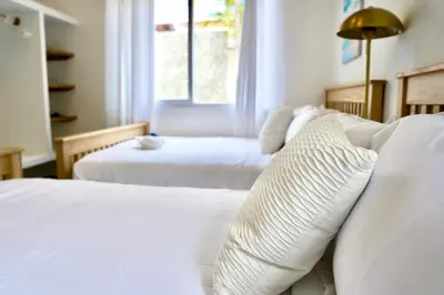 a bedroom with two beds with white sheets and a window at Villa Nakär - Oceanfront Luxury Villa in Playa Amatecampo, El Salvador in La Esmeralda