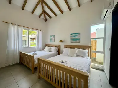two beds in a room with two windows at Villa Nakär - Oceanfront Luxury Villa in Playa Amatecampo, El Salvador in La Esmeralda