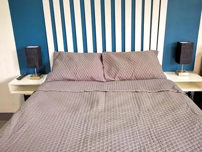 a bed with a striped headboard and two lamps on tables at Apartamento privado, Miramonte, San Salvador in San Salvador