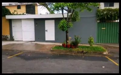 a parking lot with two white garage doors and a tree at Suite privada de 1 habitacion en San Salvador in San Salvador