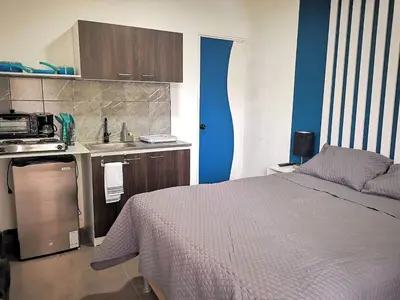 a bedroom with a bed and a kitchen with blue walls at Suite privada de 1 habitacion en San Salvador in San Salvador