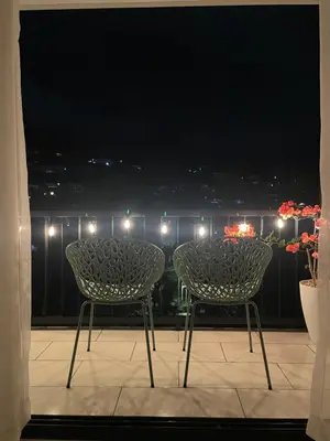 two chairs and a table on a balcony at night at Moderno apart en Col Escalón,vista,piscina,gimnasio in San Salvador