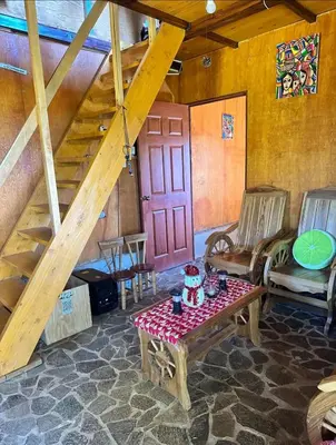 a living room with a table and a red door at Cabaña Vista Pinares San Ignacio Chalatenango in Chalatenango