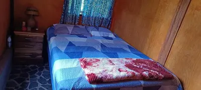 a bedroom with a bed with a blue and red quilt at Cabaña Vista Pinares San Ignacio Chalatenango in Chalatenango
