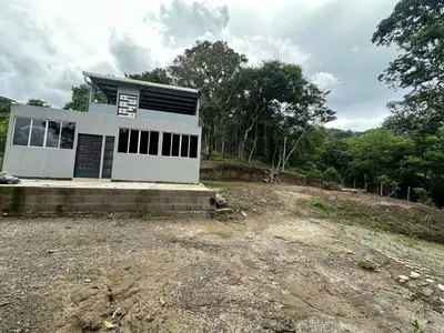 a small white house on a dirt field at Zona de Camping con casa de campo in San Salvador