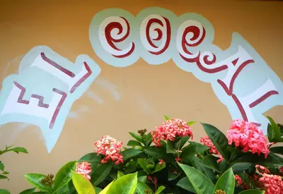 a wall with a sign that says ego and flowers at Punta Roca Surf Resort in La Libertad