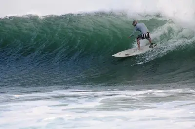 a man riding a wave on a surfboard in the ocean at Punta Roca Surf Resort in La Libertad